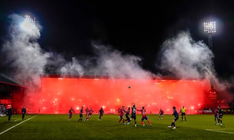 A stand is lit up with red pyrotechnics set off by Rangers fans at kick-off