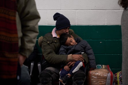 A man sleeps with his child while waiting in the local bus station in El Paso, Texas.