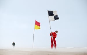 An RNLI lifeguard plants a warning flag at Portstewart Strand amid Storm Floris