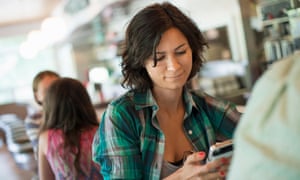 A woman in a diner, looking at her cell phone