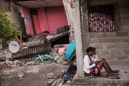 A girl checks her cell phone in front her house destroyed by the 7.2 earthquake in Les Cayes, Haiti