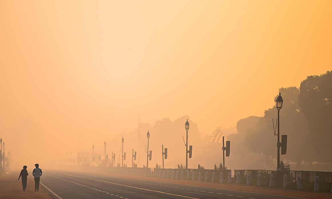 Two men walk along Rajpath amid smoggy conditions in New Delhi