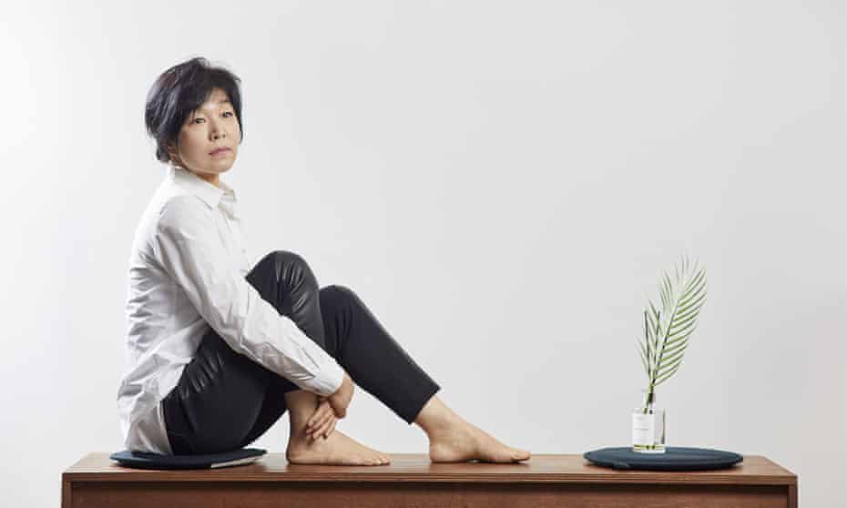 Kyung-sook Shin sitting on a wooden desk.