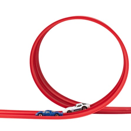 Two toy cars race along a red plastic track leading into a vertical loop