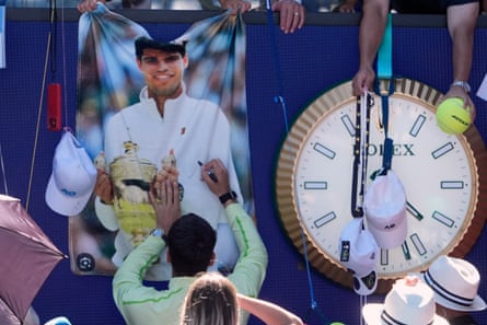 Carlos Alcaraz signs autographs after defeating Corentin Moutet in their third round match.