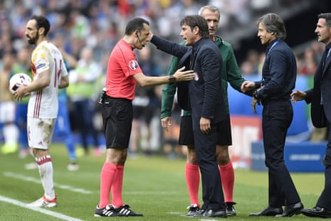 Referee Cuneyt Cakir talks to Antonio Conte after Conte thumped the ball away.