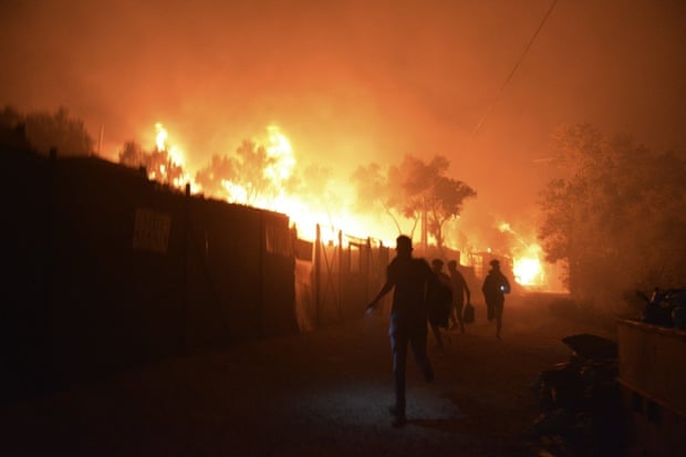 Refugees and migrants run as fire burns in the Moria refugee camp on Lesbos on Wednesday.