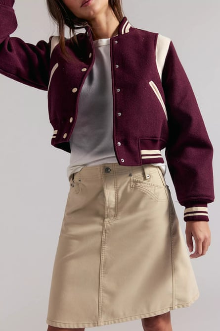 close-up of woman wearing tan skirt and burgundy varsity-style jacket