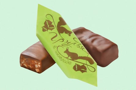 Green and brown packaging rests against two pieces of chocolate