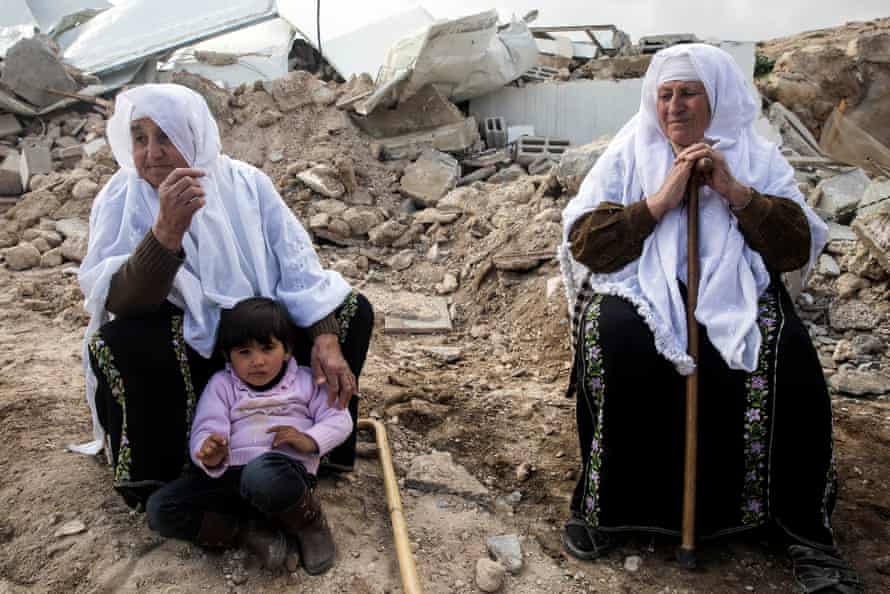 Miriam al-Shehadeh, aged 70, (right) sits in the rubble of her home
