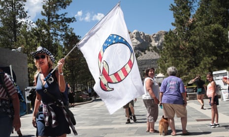 A Donald Trump supporter holding a QAnon flag visits Mount Rushmore national monument on 1 July 2020 in Keystone, South Dakota.