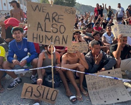 Crowd of people holding placards, one of which reads ‘We are also human’.
