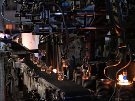 Glass tumblers are carried and dropped by factory machine.