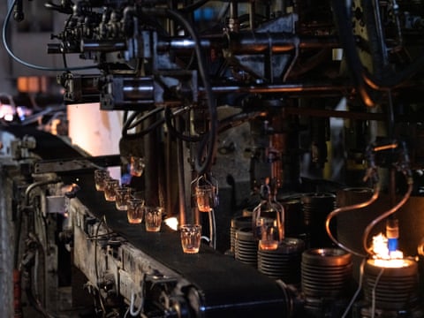 Glass tumblers are carried and dropped by factory machine.