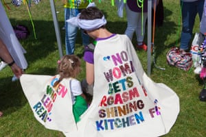 A woman and girl wear capes with embroidered slogans at the Processions artwork march, London