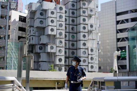 A security personnel on patrol at an area near the Nakagin Capsule Tower (background) in Tokyo, Japan.
