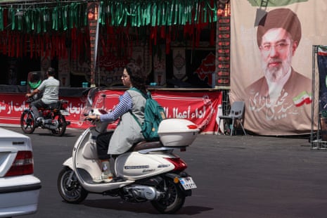A woman rides a motorbike past a banner of Iran's supreme leader Mojtaba Khamenei in Tehran.