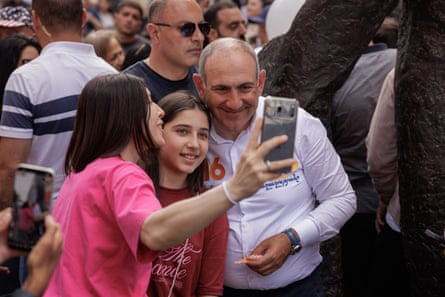 Pashinyan poses for a selfie with a woman and a girl
