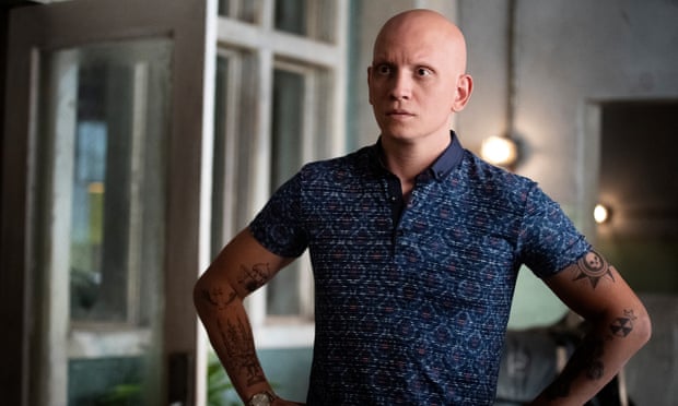 Fan favourite Anthony Carrigan as NoHo Hank in Barry. Carrigan is standing with his hands on his hips wearing a blue collared shirt