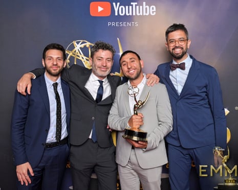 four men smile while one of them holds an award