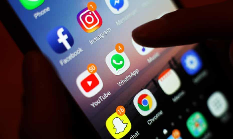 Social media app icons, including Facebook, Instagram, YouTube and WhatsApp, are displayed on a mobile phone screen