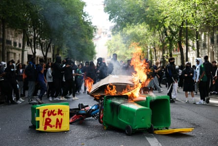 Students look at bins burning with a sentence reading “Fuck RN (Rassemblement National)“