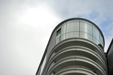 A missing window on the top floor of the block of flats, which has a curved glass frontage.