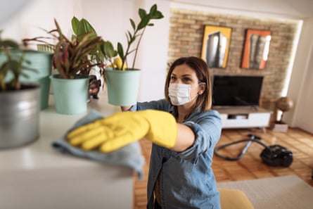 Woman wiping dust from shelf and other furniture in living roomWoman working at home, cleaning the floors, washing the laundry and cleaning up the mess in the closet during quarantine