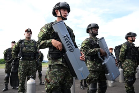 A group of soldiers carrying large gun-like anti-drone weapons