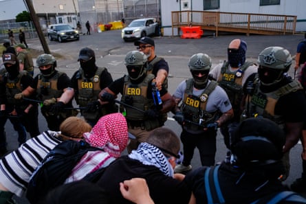 a row of officers stand outside facing a row of protesters arm in arm