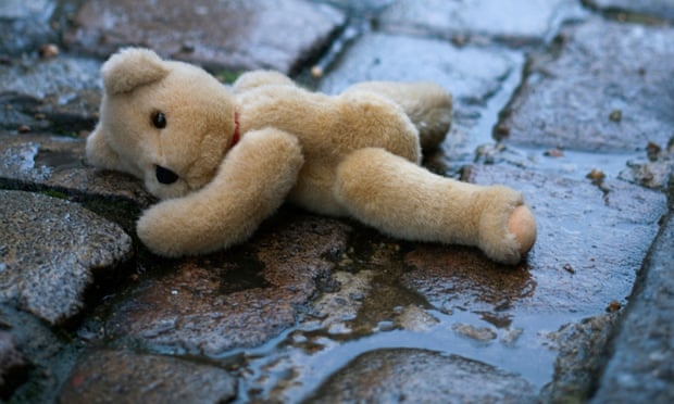 Abandoned teddy bear in wet gutter