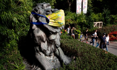 People exit the Smithsonian National Zoological Park beside a statue of a lion that is decorated with a face mask in Washington, DC, USA.Six lions and three tigers at the National Zoo have tested positive for Covid-19 and are receiving treatment, the zoo said.