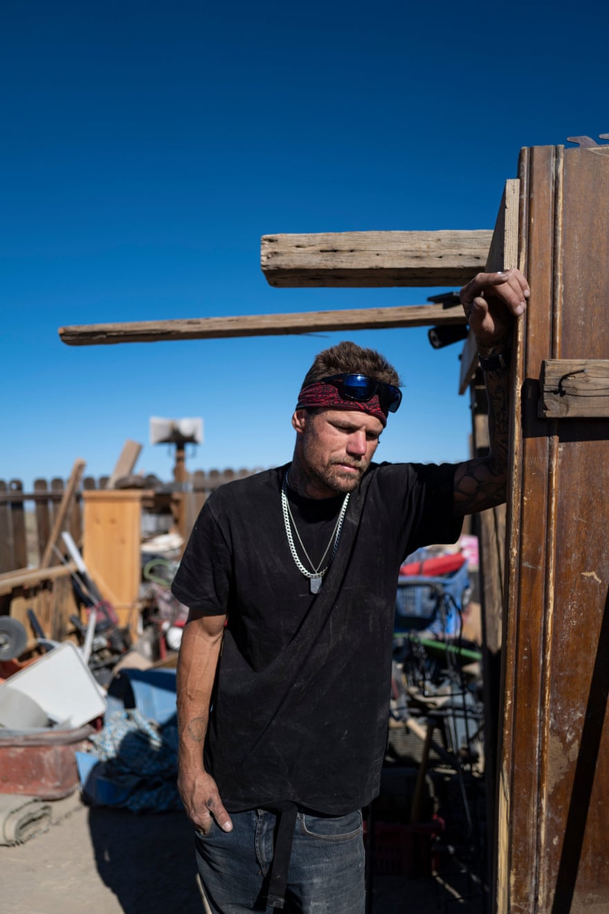 A man rests his arm on a makeshift shelter in the desert