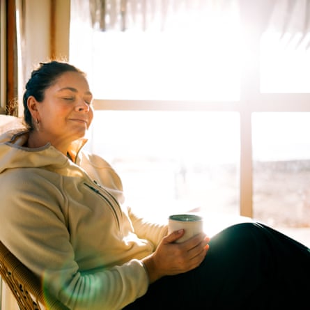 Serene woman relaxing with warm drink by sunny window