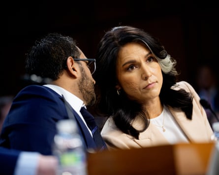 Kash Patel leans back in his seat to talk to Tulsi Gabbard as she leans sideways toward him
