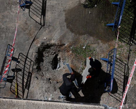 एक आपातकालीन प्रत्युत्तरकर्ता बैरिकेड्स और सावधानी टेप से घिरे गंदगी के गड्ढे में काम करता है।