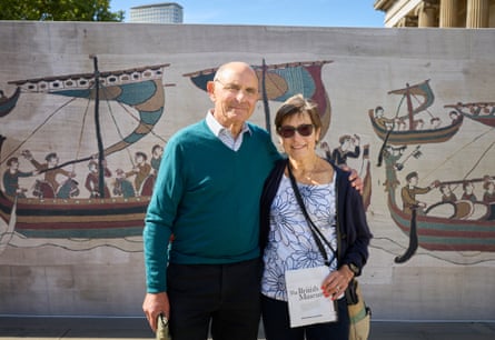 The couple stand in front of a large illustration of the tapestry outside the museum