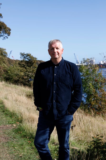 A man in navy blue stands in a field