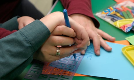 hands of teacher and special needs child learning to write