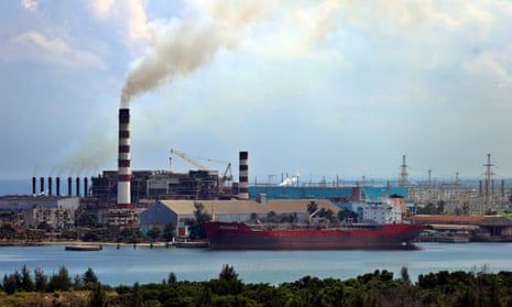 A large electrical power plant with a ship anchored beside it.
