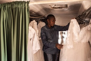 Martha Gutsa inspects wedding dress behind a green curtain inside the caravan