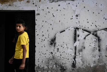 A boy walks past a shrapnel-riddled wall at the Jenin camp in the West Bank on 4 November.