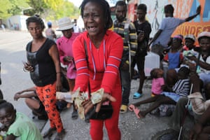 Port-au-Prince, Haiti. Rose Delpe cries as she holds out money next to other people displaced by gang war violence in the Cité Soleil are of the Haitian capital.