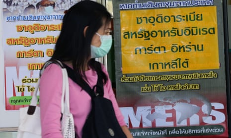 A Thai woman in a protective mask walks past signs giving information on Mers virus in Thailand. The country confirmed its first case just as an outbreak in South Korea appears to have peaked.