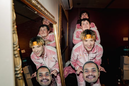 three members of a band pose for a photo while holding a cutout of the face of their fourth member