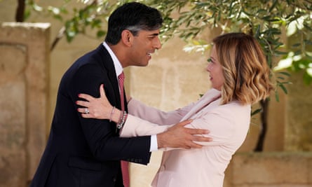 Rishi Sunak smiles and embraces Italian PM Giorgia Meloni, who looks surprised at what he is saying