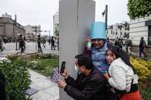 Lima, Peru: a group of people take shelter during clashes between protesters and police on the outskirts of the city, where the former president Pedro Castillo is detained