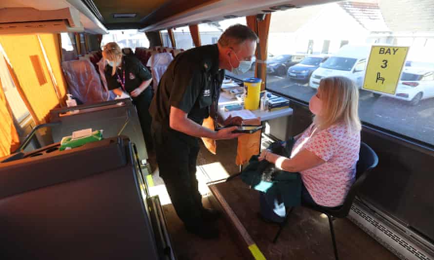 A paramedic with a patient in a coach being used as a mobile vaccination centre near Inverness, Scotland.