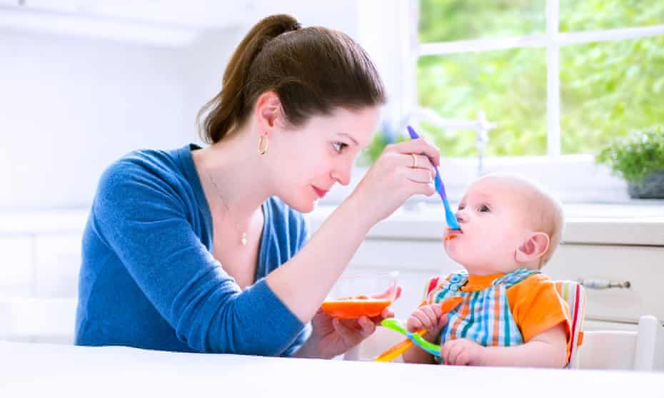 A mother feeding her baby solids