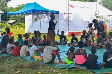 Woman speaking to children sitting on tarp
